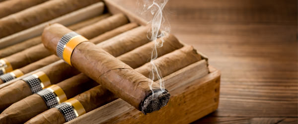 bigstock-smoking-cuban-cigar-over-box--27497000