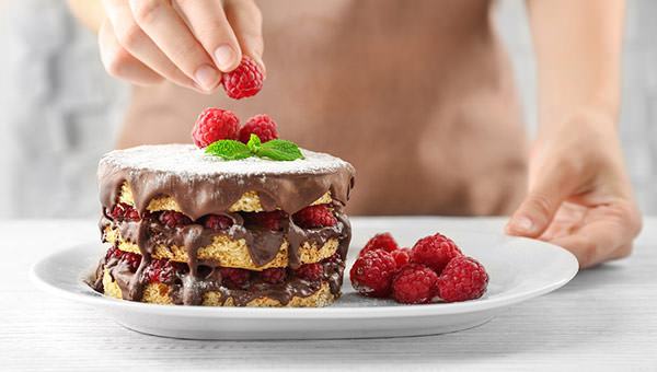 bigstock-woman-decorating-berry-cake-wi-144074426